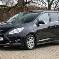 Czarny Ford C-Max na tle drzew. Wiele osób szuka pozytywnych ford c max opinie przed zakupem.