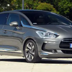 Szary Citroen DS5 na tle zieleni. Wiele osób szuka o nim **citroen ds5 opinie**, a ten model prezentuje się elegancko.