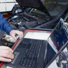 Mechanik diagnozuje uszkodzony sterownik LPG, analizując objawy na laptopie.