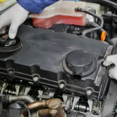 Mechanik w białych rękawiczkach sprawdza silnik. Może to być związane z nieszczelna odma objawy, które wymagają uwagi.