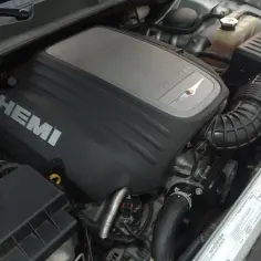 Silnik 5.7 Hemi z napisem HEMI na pokrywie. Widoczny układ dolotowy i inne elementy komory silnika.