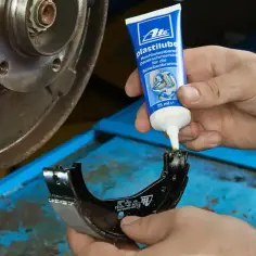 Mechanik aplikuje smar ATE Plastilube na prowadnice zacisku hamulcowego. To kluczowy krok, by zapewnić płynne działanie hamulców.