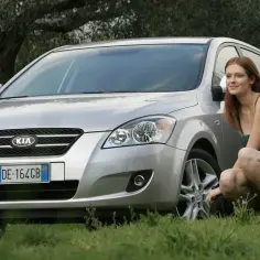 Kobieta w sukience przy srebrnym Kia Ceed 1.4 benzyna, obok koń i pieski.