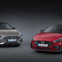 Dwa modele Hyundai i30: jeden w kolorze złotym, drugi czerwony, prezentują nowoczesny design i sportowy charakter.