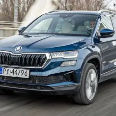Niebieski Skoda Karoq w ruchu, z kierowcą za kierownicą. Sprawdź aktualną skoda karoq cena.