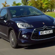 Elegancki, granatowy Citroen DS3 z kierowcą w okularach przeciwsłonecznych jedzie po drodze.