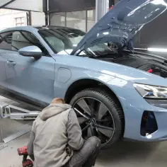 Mechanik wymienia opony w szarym Audi. Zastanawiasz się, ile trwa wymiana opon? Zazwyczaj to szybka usługa.