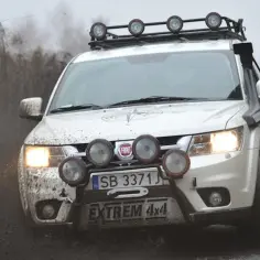 Biały Fiat Freemont z dodatkowym oświetleniem i snorkel'em pokonuje błotniste tereny. Wiele osób szuka takich aut, czytając fiat freemont opinie.