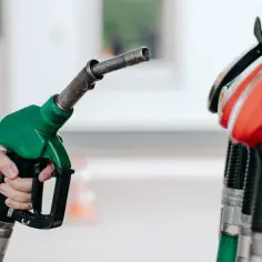 Zielona dysza dystrybutora paliwa w dłoni, gotowa do tankowania. Pb 95 czeka.