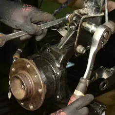Mechanik dokręca śruby przy piaście, gdzie znajduje się łożysko w kole.