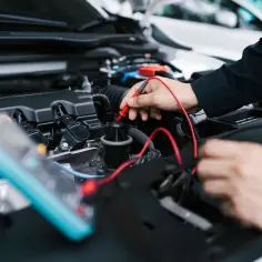 Mechanik sprawdza silnik samochodu multimetrem. Potrzebujesz szybkiego **service jetzt**?