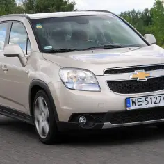 Złoty Chevrolet Orlando na drodze. Kierowca w środku, widok z przodu. Wiele osób szuka chevrolet orlando opinie przed zakupem.