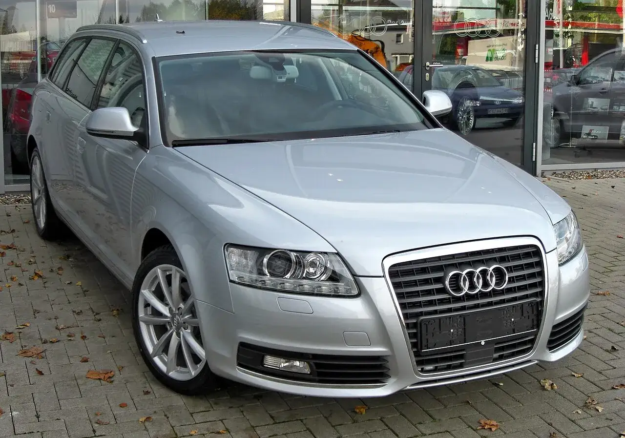 Srebrne Audi C6 Avant stoi przed salonem samochodowym.