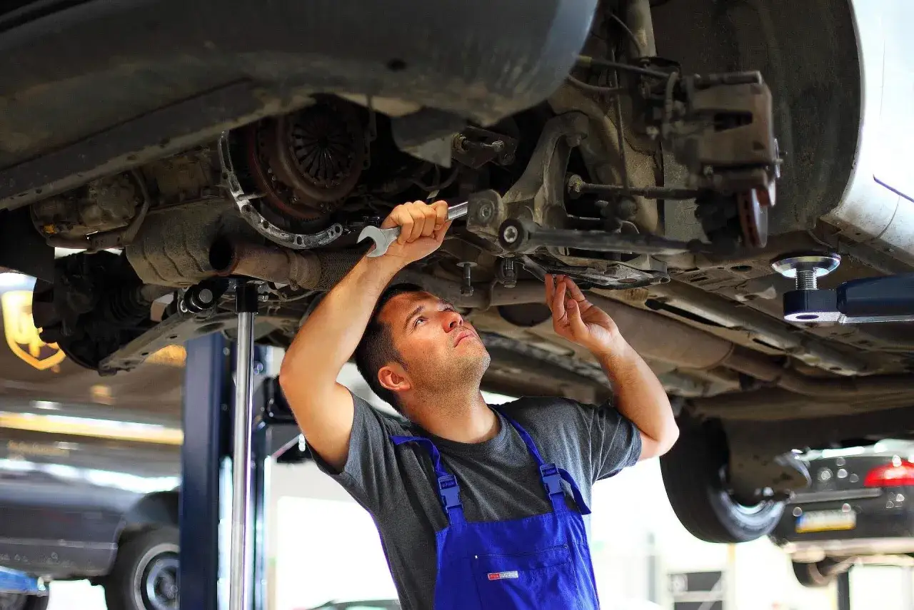 Mechanik dokonuje wymiany tulei wahacza, używając klucza do precyzyjnego dokręcenia śrub.
