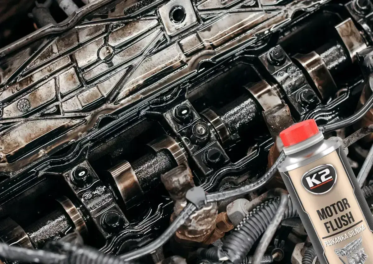 Widok wnętrza silnika z widocznymi wałkami rozrządu i butelką płukanki silnika K2 Motor Flush.