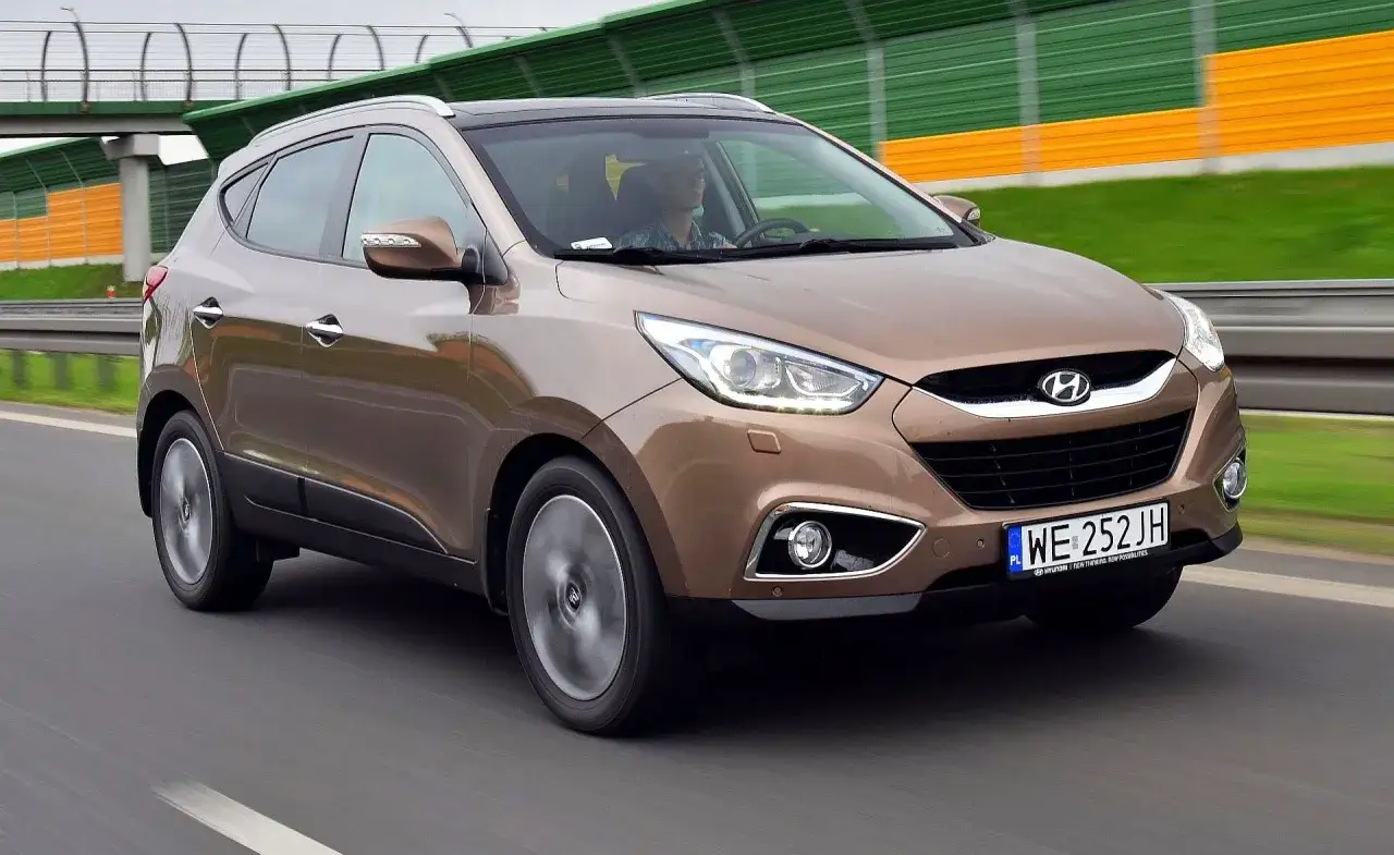 Brązowy Hyundai ix35 na drodze. Wiele pozytywnych hyundai ix35 opinie potwierdza jego wszechstronność.