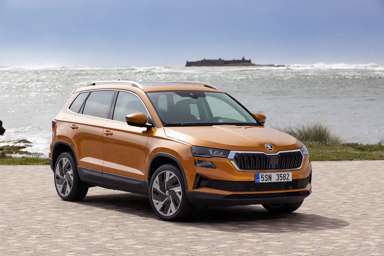 Pomarańczowy Skoda Karoq na tle morza. Sprawdź atrakcyjną skoda karoq cena i wybierz swój wymarzony SUV.