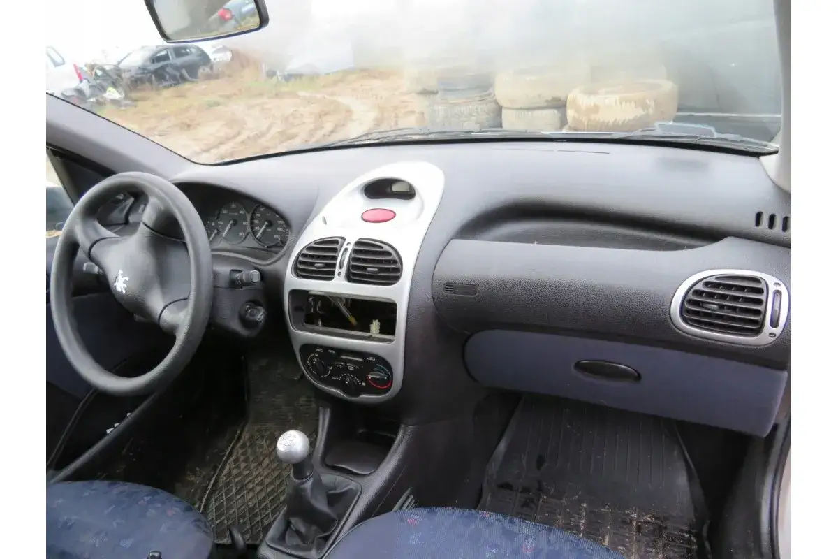 Wnętrze Peugeot 206 Plus: kierownica, deska rozdzielcza z radiem i nawiewami, dźwignia zmiany biegów.