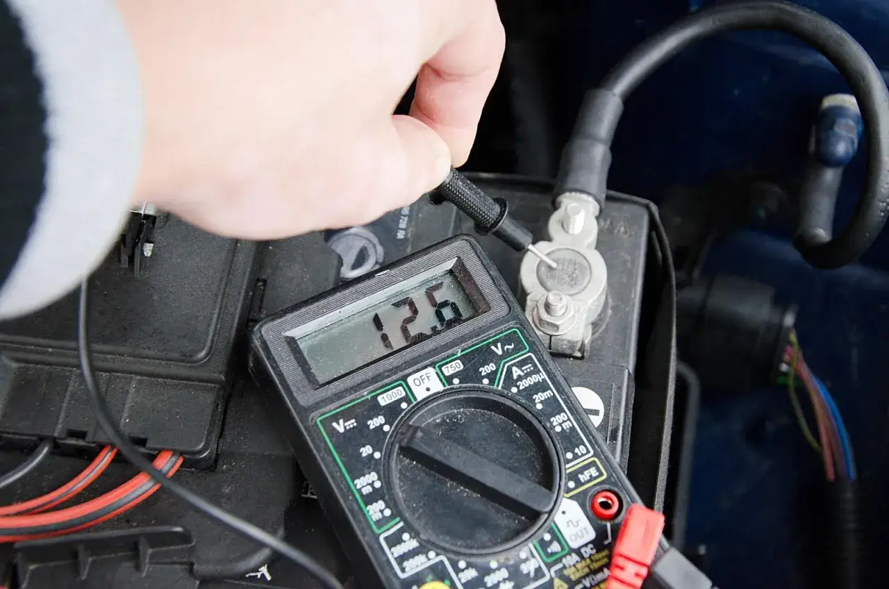Sprawdzanie akumulatora multimetrem. Wynik 12.6V pokazuje, że jest naładowany.