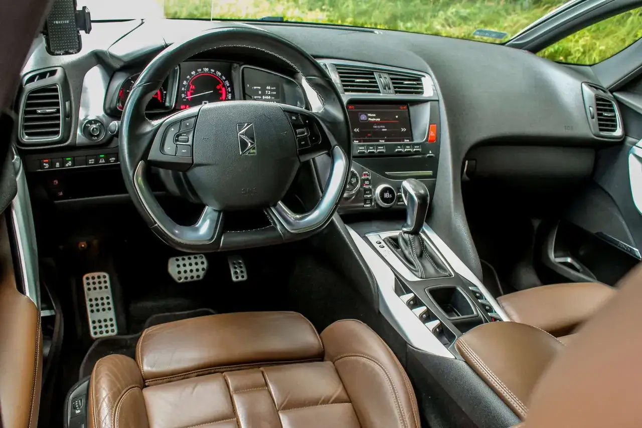 Wnętrze Citroena DS5 z brązową skórzaną tapicerką i nowoczesnym panelem. Kierowca może sprawdzić opinie o tym modelu na ekranie.