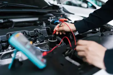 Mechanik sprawdza silnik samochodu multimetrem. Potrzebujesz szybkiego **service jetzt**?
